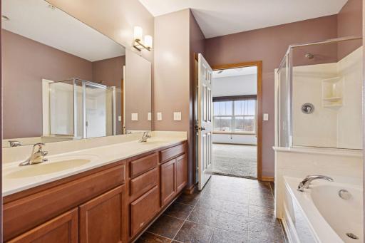 Private primary bathroom with double vanity, ample cabinet storage, soaking tub, and separate shower.