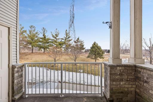 Private covered balcony overlooking open green space and mature trees, offering peaceful views and direct access to the nearby walking path and park.