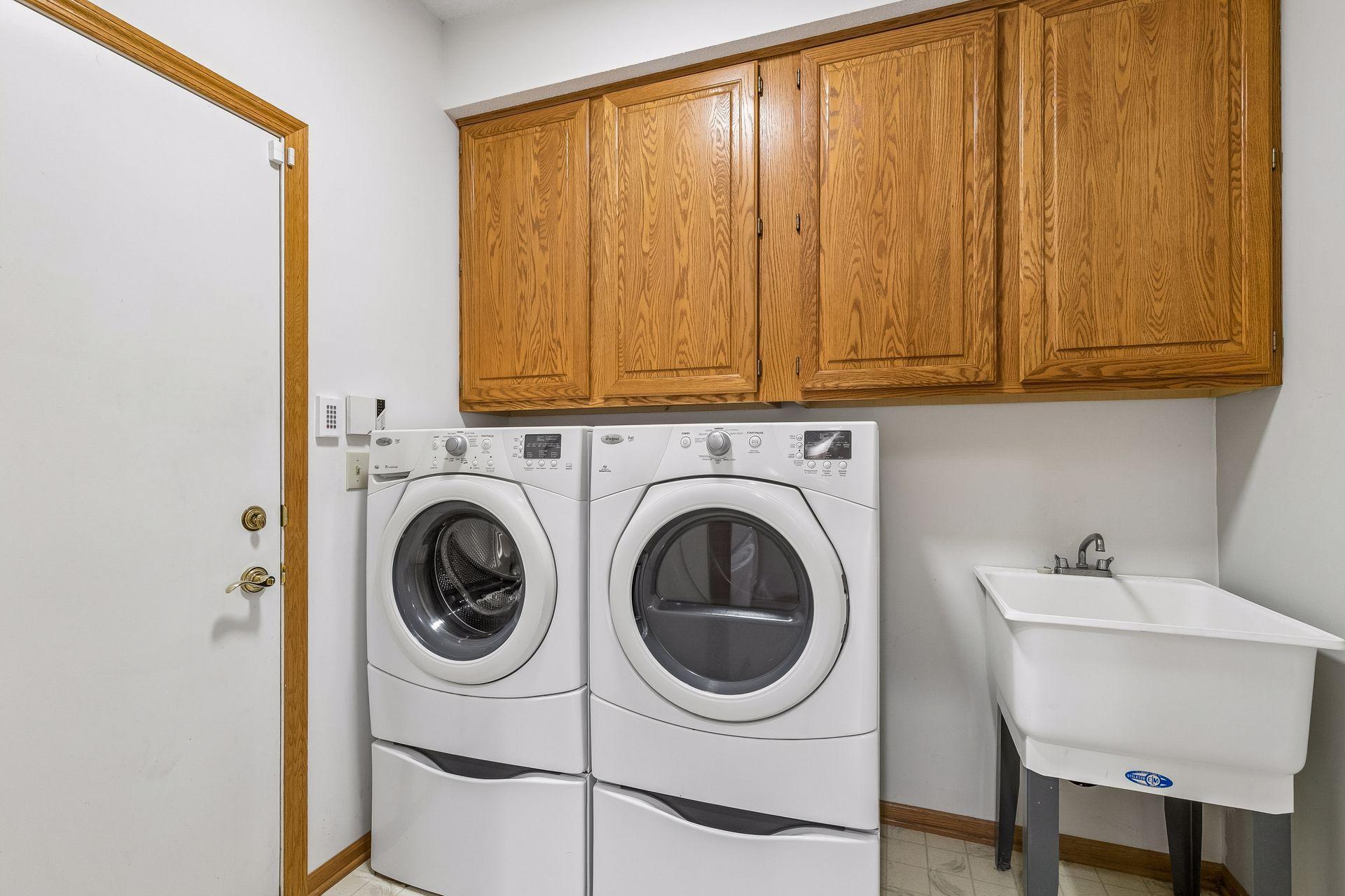 Laundry Room just off the kitchen includes large pedestal front loaders, cabinets and a laundry tub