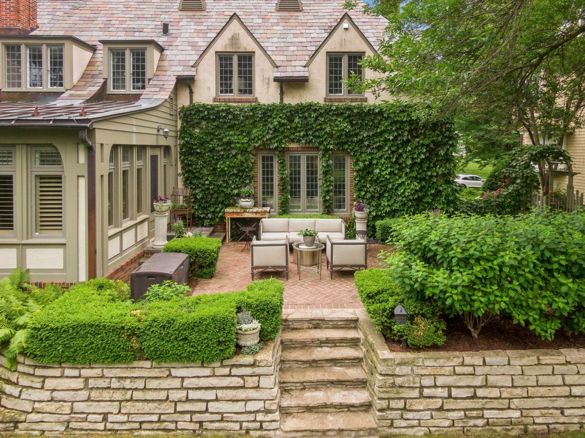 Professionally landscaped double lot with stone retaining walls and steps leading to an expansive flat lawn and hot tub patio.