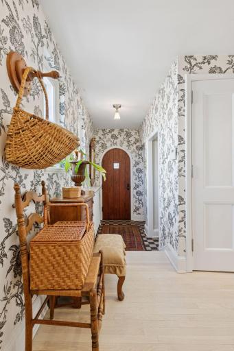 The charming side entrance and hallway lead to the main level powder room, mud room, 2-car heated garage, and a secondary staircase to the lower level.