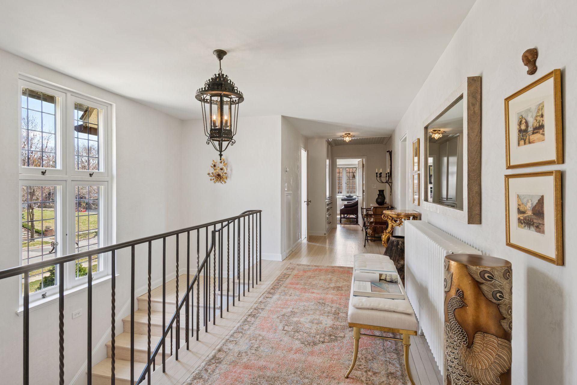 The upper hallway leads to the primary suite and two ensuite bedrooms with hall access to a full bath. A door at the opposite end leads to a separate wing for the 4th and 5th bedrooms and another full bath.