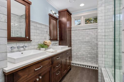 The hallway bathroom features heated floors - yes, please! And the designer touches with the timeless marble tile, heated floors, and wonderful storage.