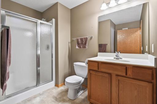 A bright and functional three-quarter guest bathroom features neutral tone flooring and paint.