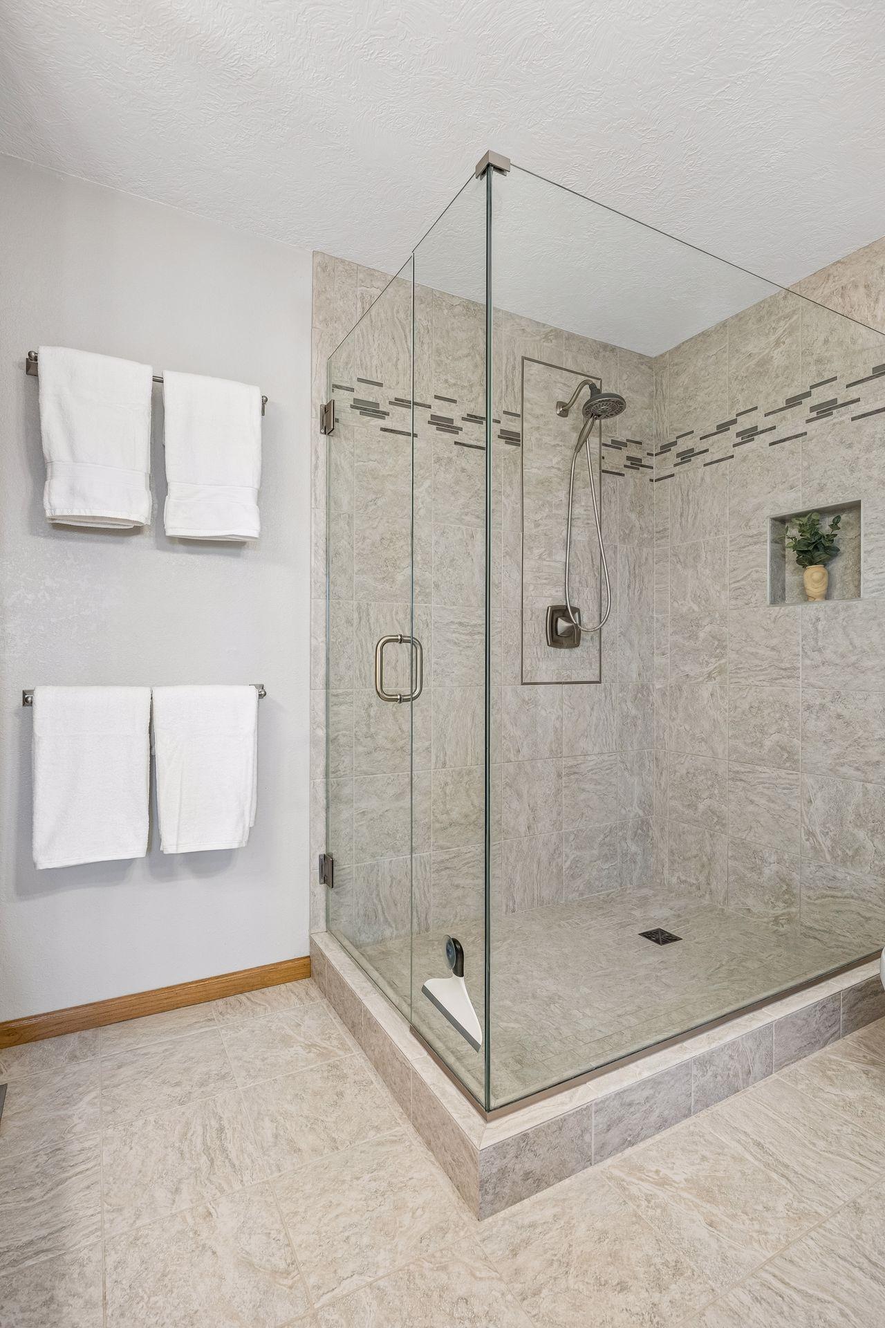 Walk-in tile shower with glass surround.