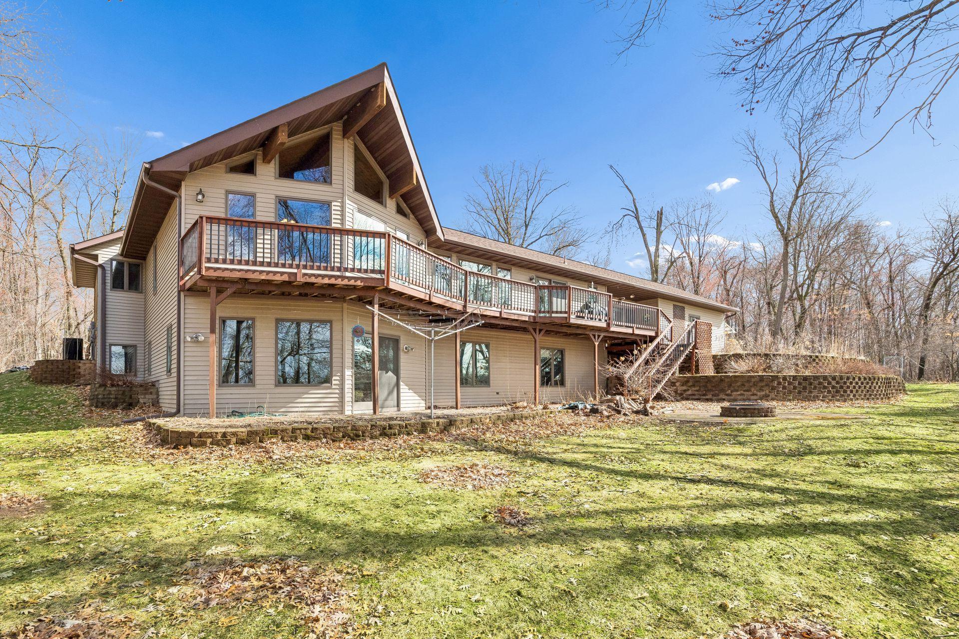 The back of the home features an expansive deck, beautiful windows, and stairs leading to the patio below.