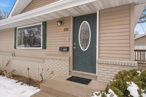 Welcoming front entrance with decorative glass door, covered entry, and exterior lighting. The large picture window beside the entry adds character while allowing abundant natural light into the main living space.