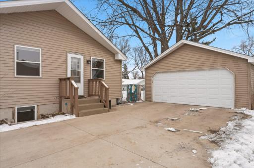 Side exterior featuring a concrete driveway, detached two-car garage, and convenient secondary entry with steps and railing. (New garage door 2019, New concrete driveway 2018)