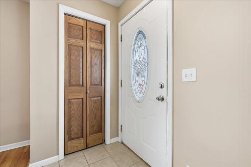 Welcoming entry with decorative glass front door, tile flooring, and convenient coat closet. Functional layout provides a smooth transition into the main living spaces.
