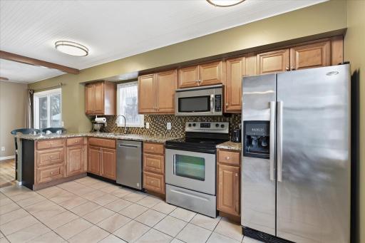 Updated kitchen featuring abundant maple cabinetry, tile flooring, and stainless steel appliances. Functional layout offers ample prep space and storage. New dishwasher 2021.