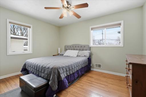 Bedroom #1 with hardwood floors, neutral walls, and multiple windows allowing for natural light and flexible furniture placement.
