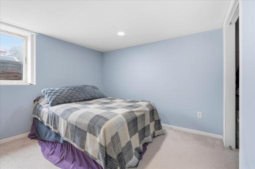Lower-level bedroom with egress-style window, neutral finishes, and closet space, suitable for office, or hobby space.