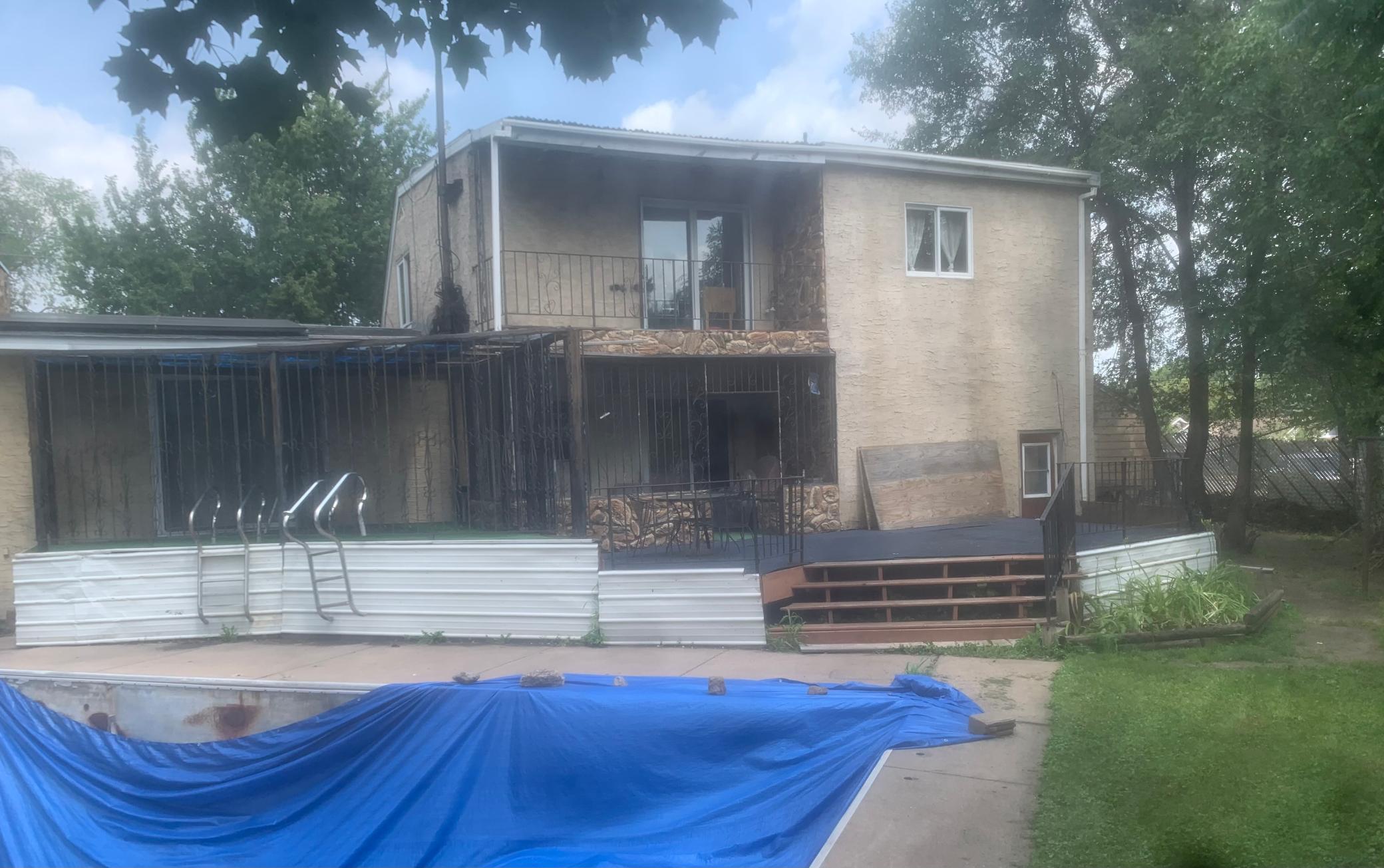 Back of the home. The balcony is off the primary bedroom. The pool is now tarped for safety reasons.
