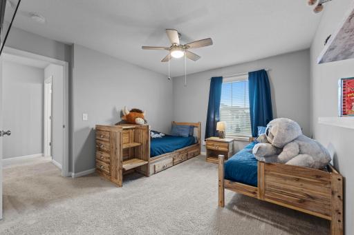 2nd Bedroom on upper level with custom window treatments, ceiling fan, tinted windows, built-in shelving.