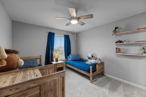 2nd Bedroom on upper level with custom window treatments, ceiling fan, tinted windows, built-in shelving.