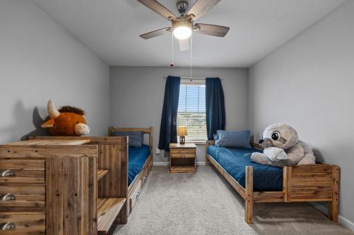 2nd Bedroom on upper level with custom window treatments, ceiling fan, tinted windows, built-in shelving.