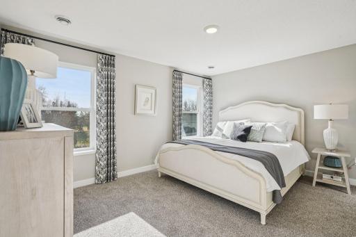 An oasis of its own, the primary suite offers the perfect escape. There's immediate access to a private bathroom that features dual sinks and a large shower. Photo is of model home. Colors and options may vary.