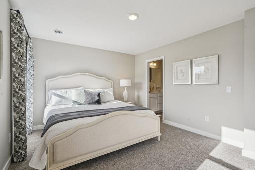 An oasis of its own, the primary suite offers the perfect escape. There's immediate access to a private bathroom that features dual sinks and a large shower. Photo is of model home. Colors and options may vary.