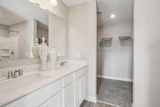 An oasis of its own, the primary suite offers the perfect escape. There's immediate access to a private bathroom that features dual sinks and a large shower. Photo is of model home. Colors and options may vary.