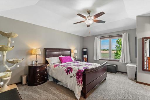 Private, Primary bedroom with tray ceiling, neutral carpeting and paint. Features a private, luxury bathroom and walk-in closet.