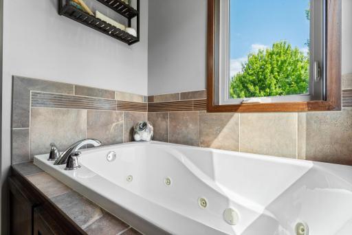 Relax at the end of the day in this jacuzzi tub. Corner windows fill this primary bathroom with an abundance of natural light.