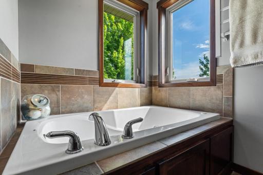 Relax at the end of the day in this jacuzzi tub. Corner windows fill this primary bathroom with an abundance of natural light.