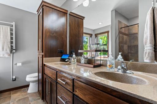 Primary bathroom with double sinks, Corian countertops and tiled floors.