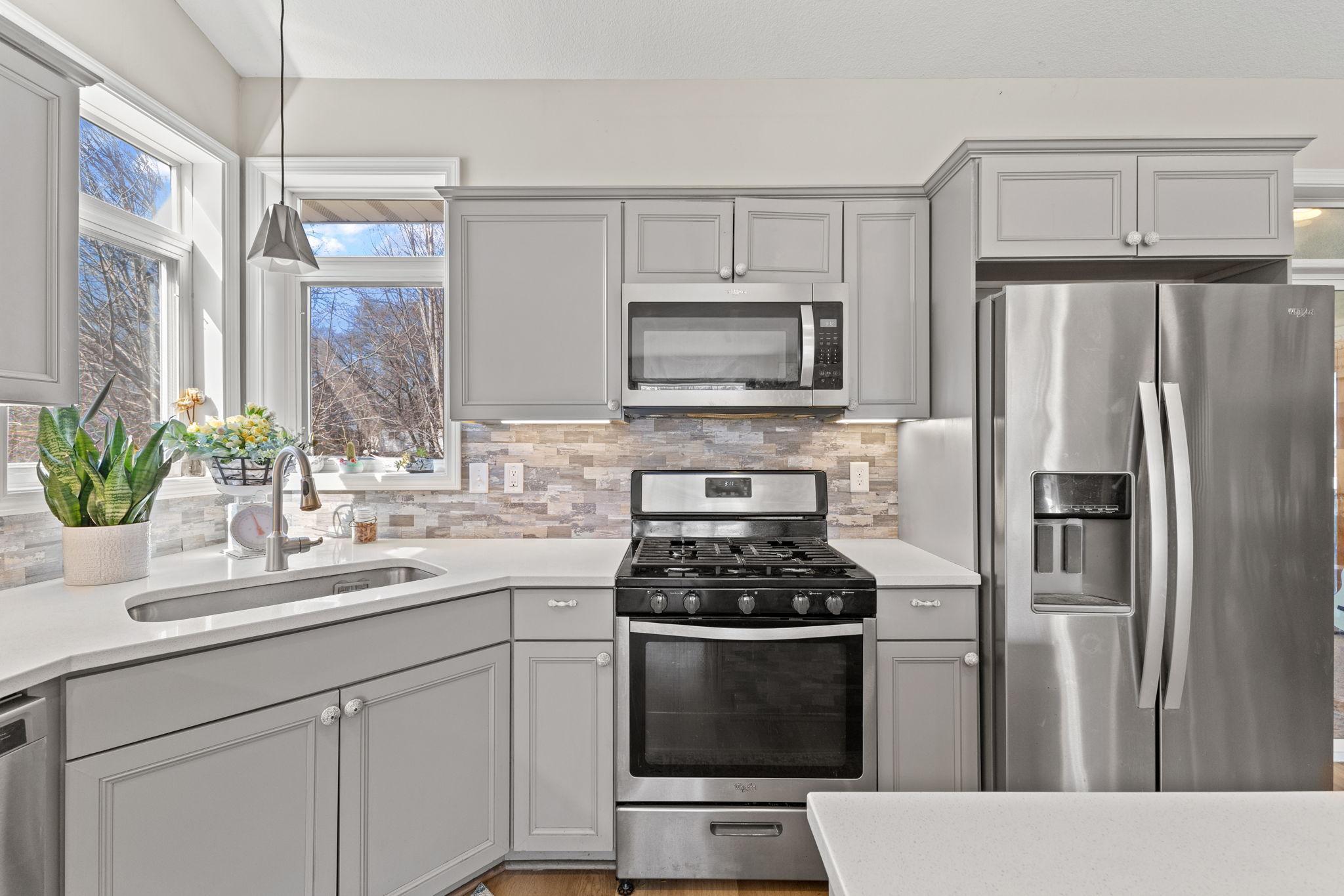 The modern kitchen boasts abundant storage/prep space, sleek hard surface countertops, and a stylish backsplash.