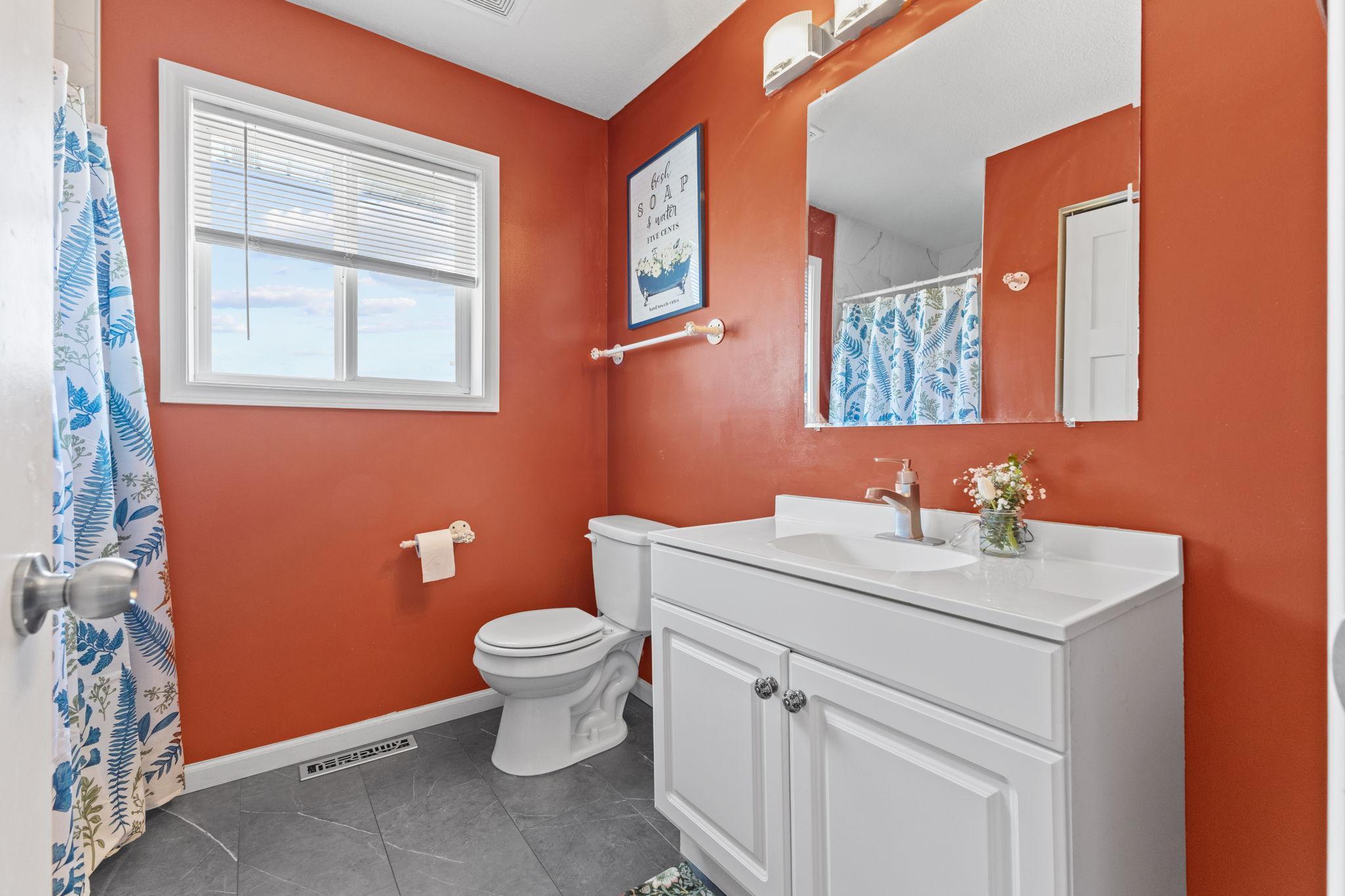 Your own private 3/4 bath with a crisp white vanity, tiled floors, and a window for natural light.