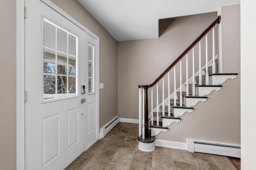 Gracious Front Entry Foyer with Original Curved Newel Post, Updated Front Door and Sidelight Window plus updated Tile Flooring.