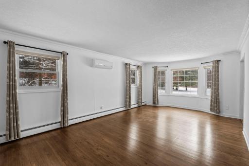 Large Living Room with Front Bay Window, Windows have all been replaced, Hardwood Floors are Original and have been refinished. AC part of the Central Mini-split System.