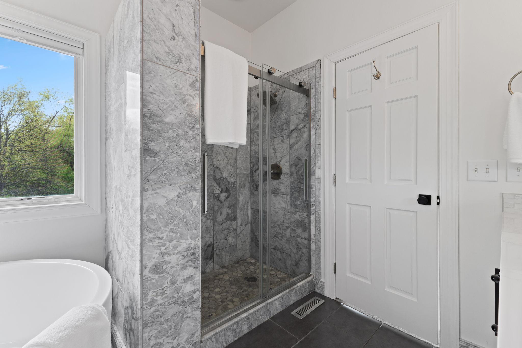 Beautifully tiled walk-in shower with glass sliding doors.