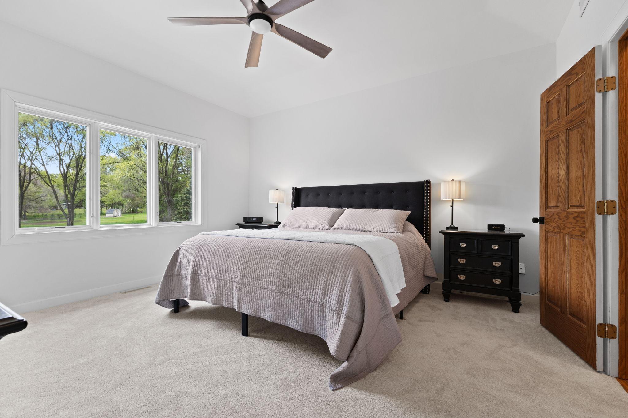 This space offers neutral tones, a large window, and a ceiling fan for year-round comfort.