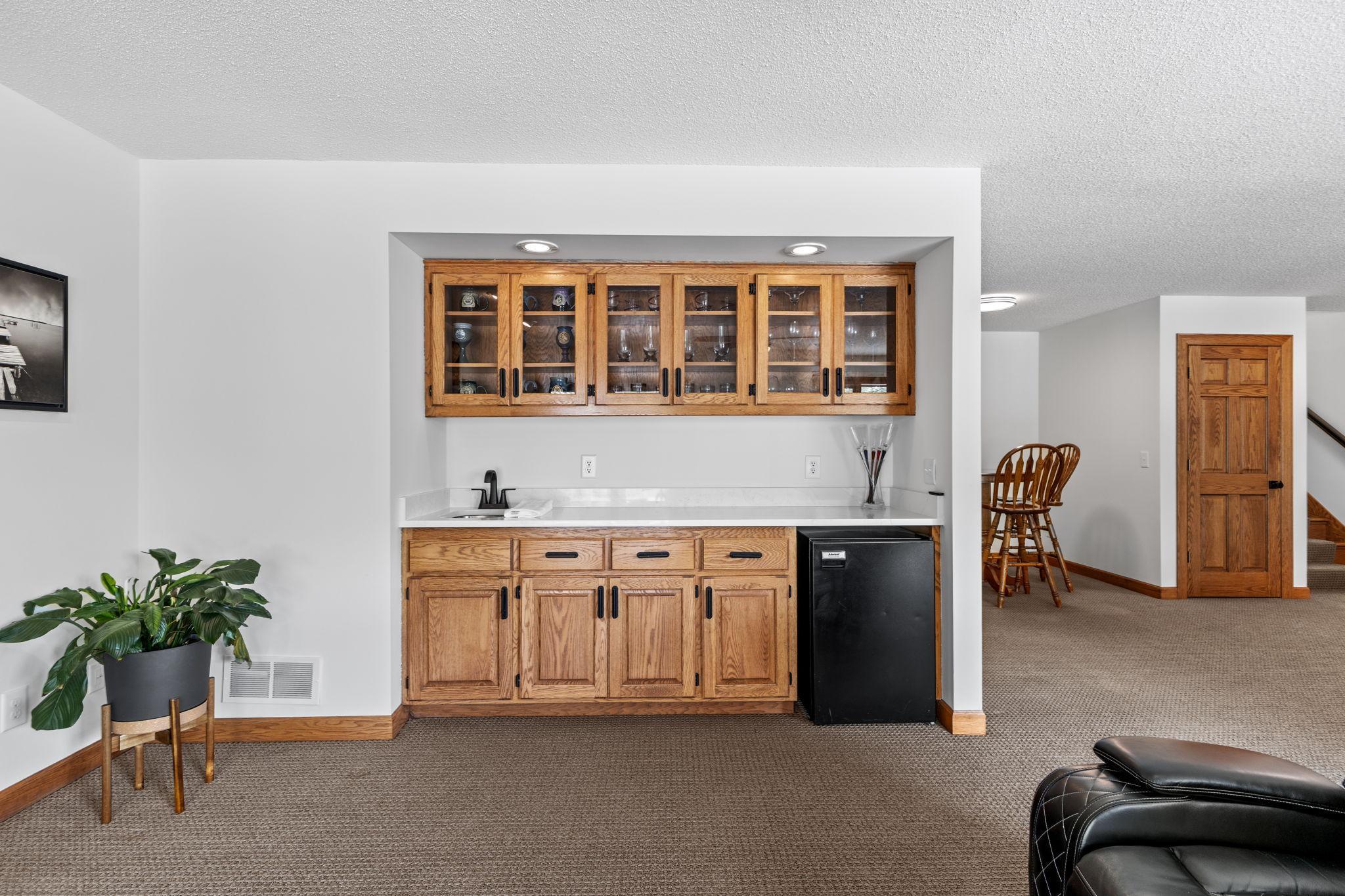 Cheers to easy entertaining! The wet bar featuring quartz countertops creates the perfect setup for mixing drinks and gathering with friends and family.