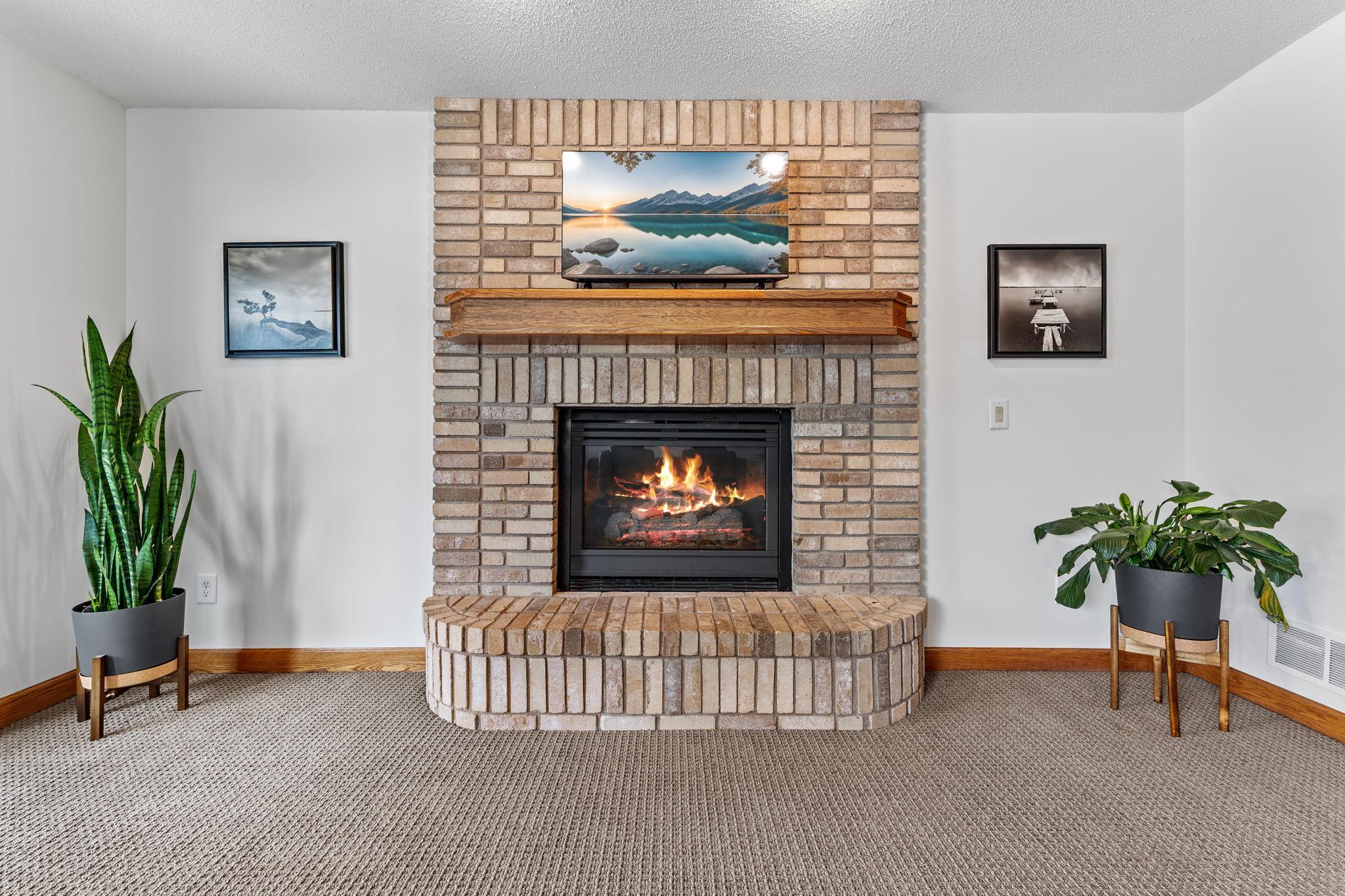 The brick fireplace adds warmth and a cozy ambiance to the lower level.