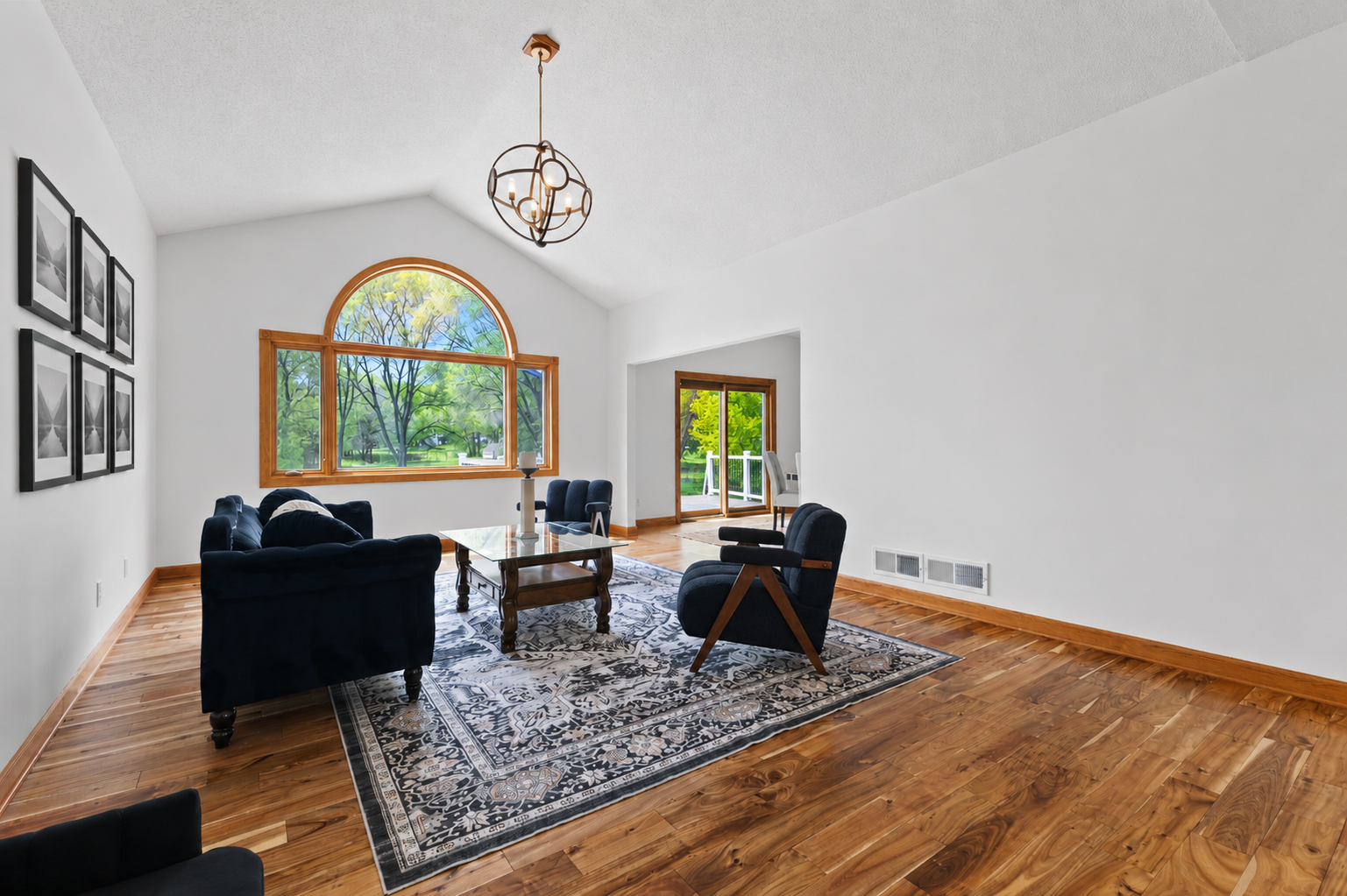 The living room features vaulted ceilings and impressive windows overlooking the private backyard oasis.