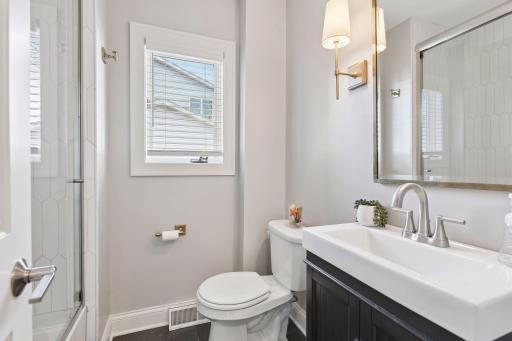 Beautifully updated main floor bathroom with full-height tile in the shower, glass door, niche, and stylish modern fixtures.
