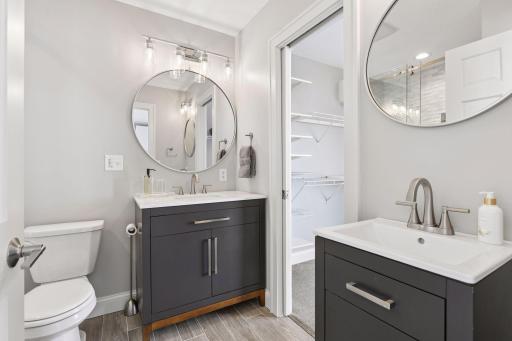 The updated primary bathroom features a tile shower, tile floors, dual vanities, and modern finishes, creating a luxurious and serene cozy retreat.
