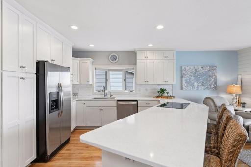 Spacious kitchen with white enameled cabinetry, stainless appliances, induction cooktop and quartz countertops.