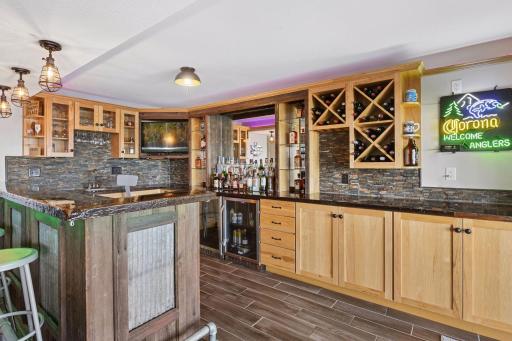 Complete lower level bar with tile floors, slate backsplash, beverage coolers, ice maker, and under-cabinet lighting, creating the ultimate space for pizza nights, cocktails, and lake house fun.
