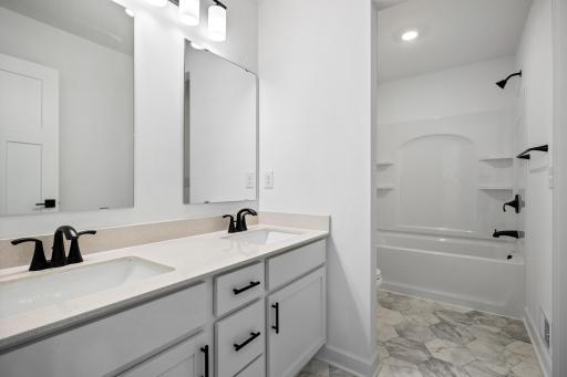 This full bathroom is conveniently located on the second floor and showcases dual sinks and a shower-tub combination.
