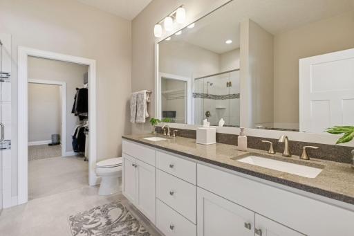 Double sink in the primary bathroom with cabinet space and storage. Walk through into your closet as well from here. Great space.