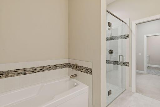 Bath tub and a shower in the primary bathroom. Elegant tiling done to match the bath to the shower. Don't miss the heated floors!