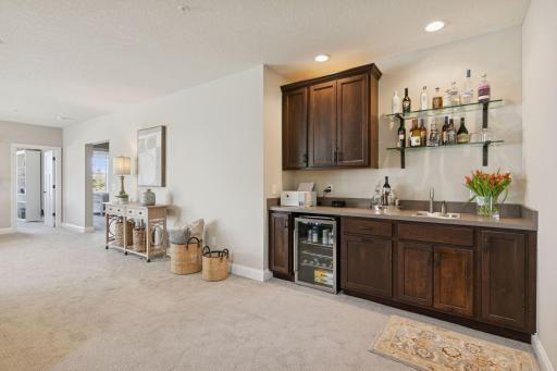 Wet bar in the basement with a beverage fridge that comes with the house, beautiful shelving for display.