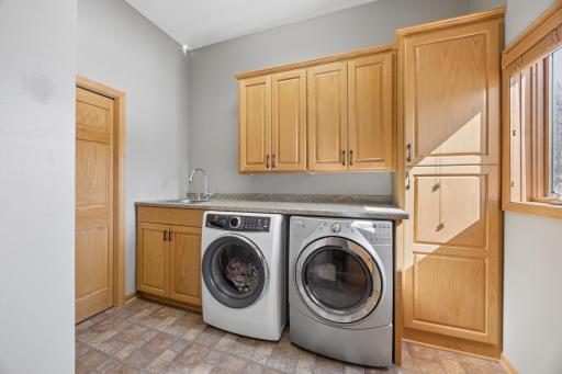 Main floor laundry! As a bonus, this home offers two washers and two dryers! This is the main laundry with another area in the lower level. The built-in cabinets and sink add to the functionality. Enjoy natural light from the window as well!