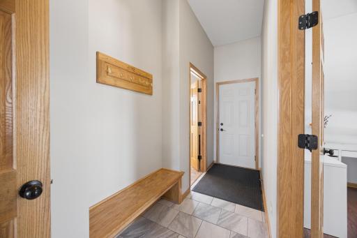 The new tiled floor hallway with a bench for easy transitions from the garage. Access to the laundry is on the left, main floor bedroom to the right. There is also a 3/4 bathroom in this hallway.
