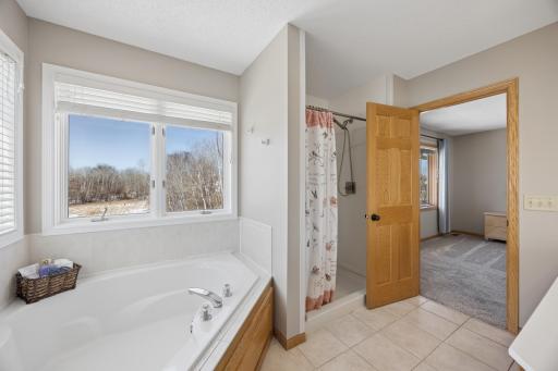 The primary bathroom including a large soaking tub and separate shower. Plenty of natural light enters this space with views below of nature!