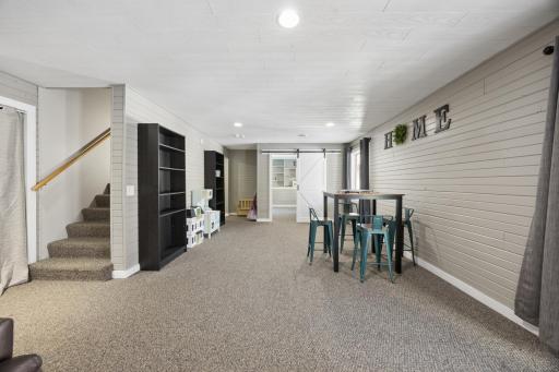 This angle of the lower level shows the 5th bedroom ahead through the barn doors and the stairs leading up to the main level. Ahead and to the left is the 3/4 bathroom and storage/laundry.