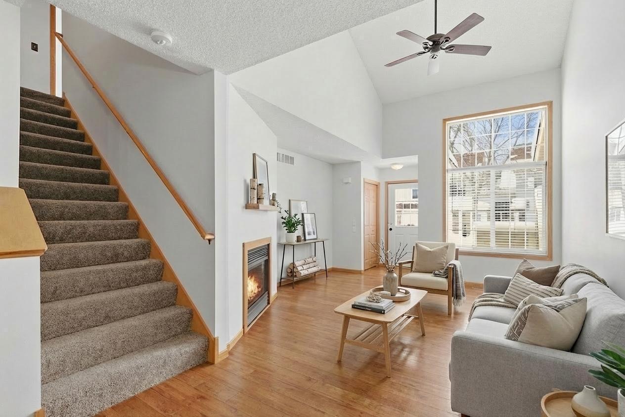 Spacious and inviting vaulted great room with cozy gas fireplace, ceiling fan, double high windows, open flow to dining room and kitchen. Virtually staged.