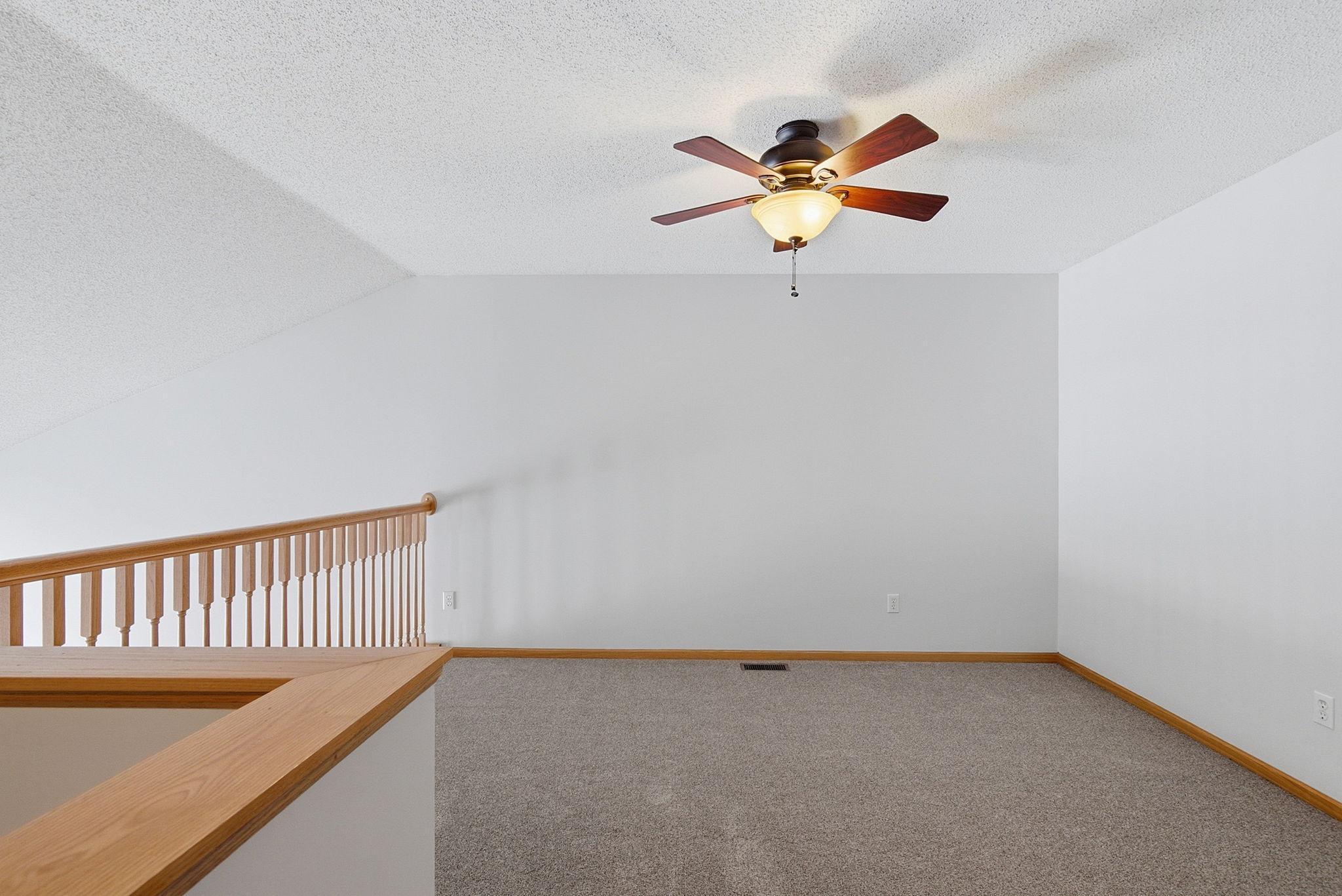 Upper level loft open to main level has ceiling fan with lights.
